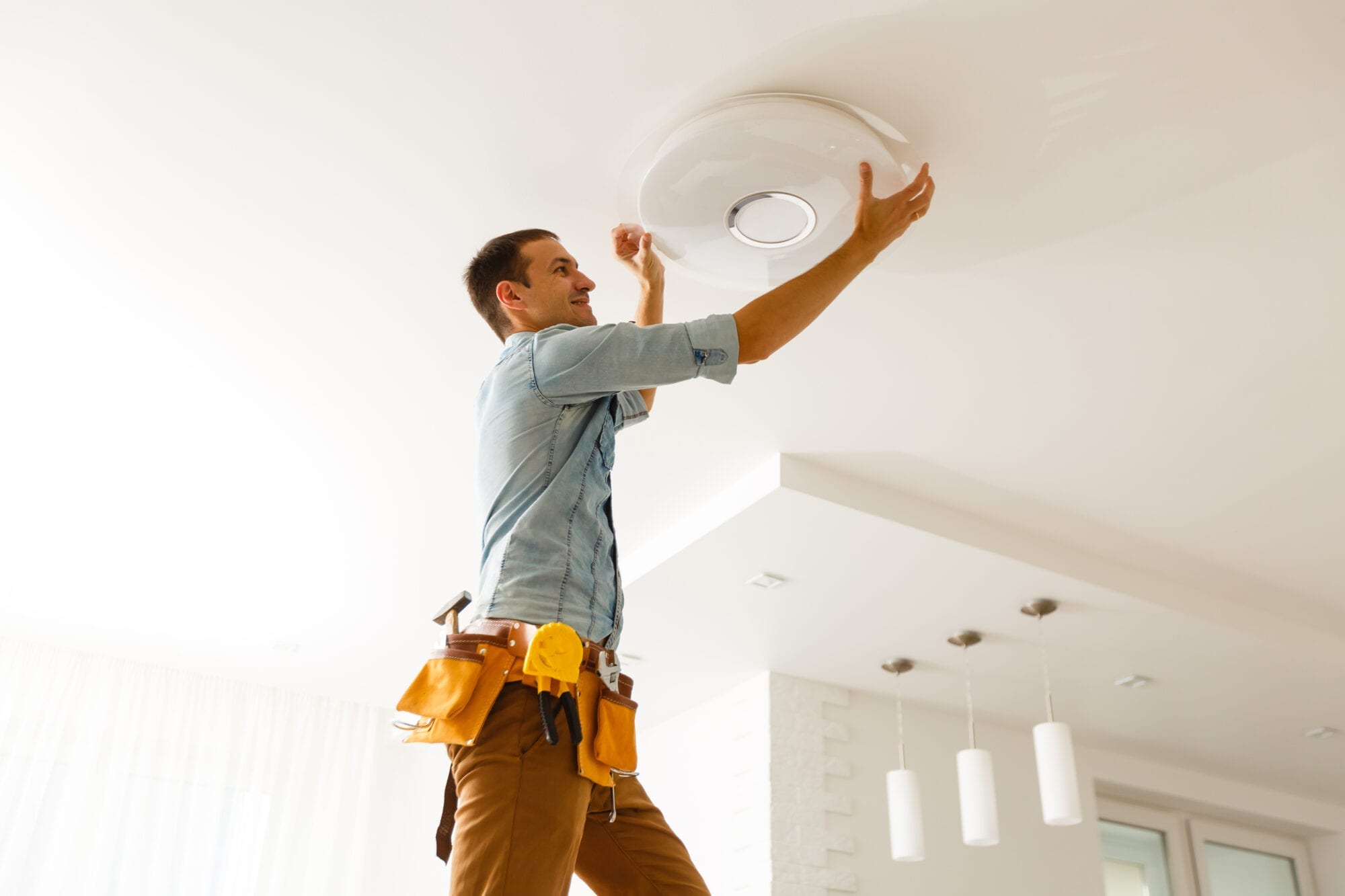 Electrician is installing and connecting a lamp to a ceiling.